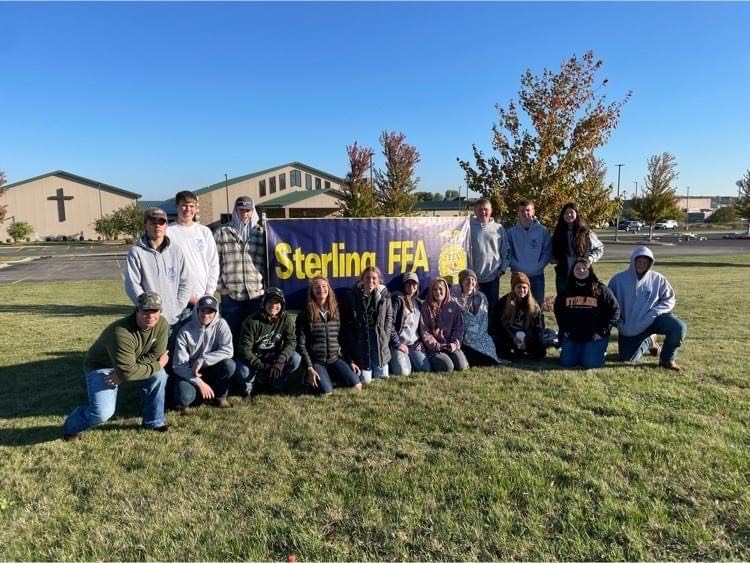 Sterling FFA members sit in front of Sterling FFA sign before Autumn Ag day starts to promote their first-ever Autumn Ag Day. 