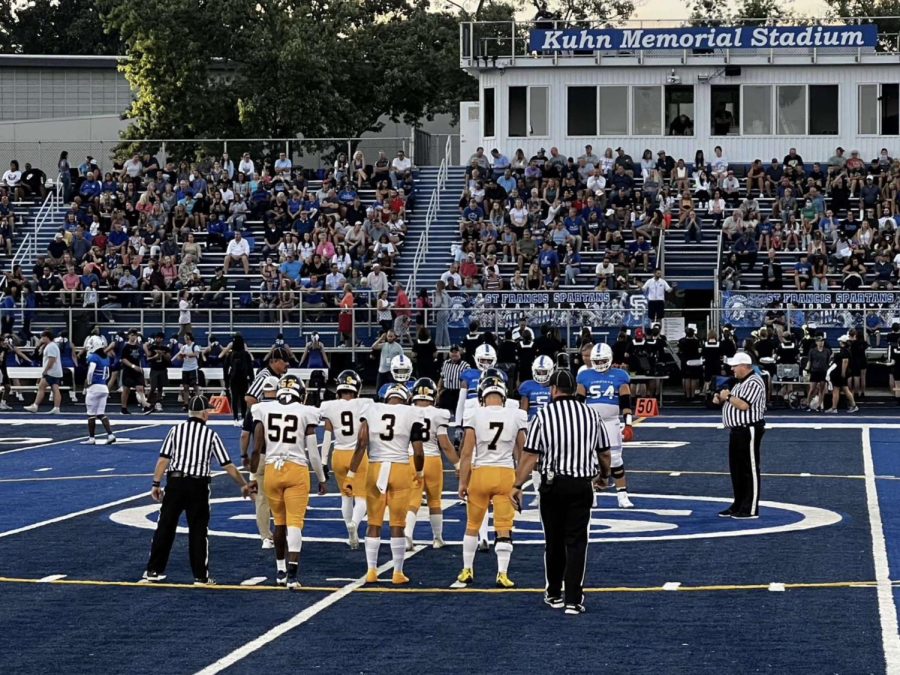 All six football captains head to the middle of the field for the coin against St. Francis. Football captains are voted on by the rest of the team before the season starts. 