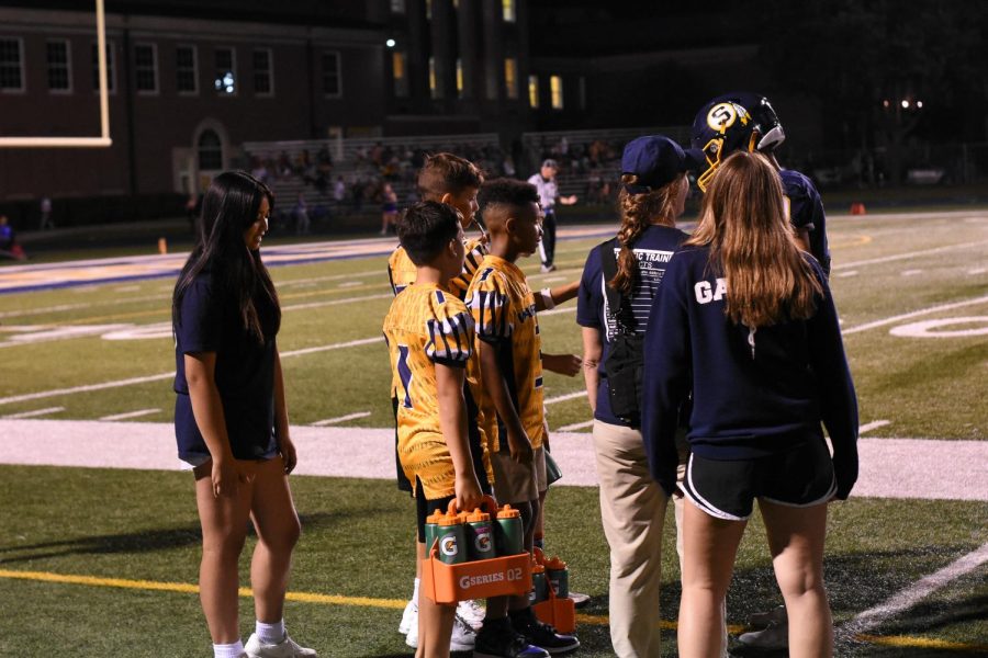Athletic trainers stand on the sidelines waiting to help at any moment. Trainers prepared football players all week for the Friday night game.