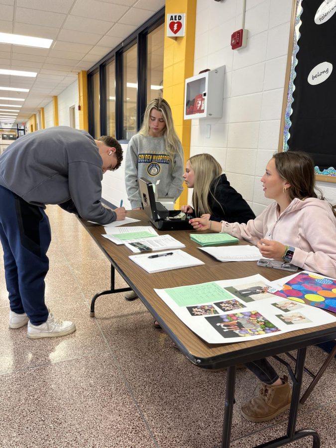 Juniors Macie Brady and Neveah Frey sell prom tickets during lunch A. Students can purchase tickets during both lunches and after school in the commons. 