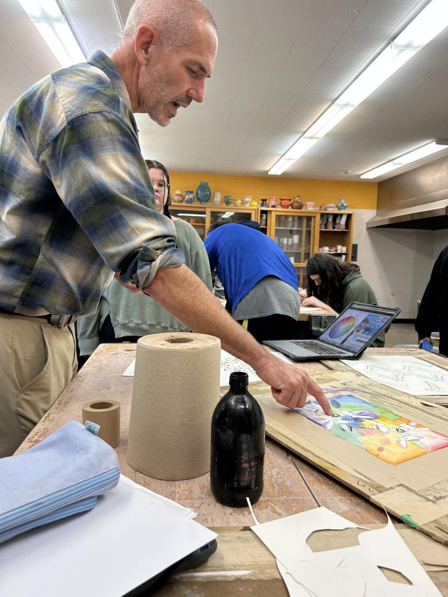 Art teacher Stuart Roddy presents an example of the pieces 2D Art 2 are currently working on. Students are completing their pieces by adding watercolor. 