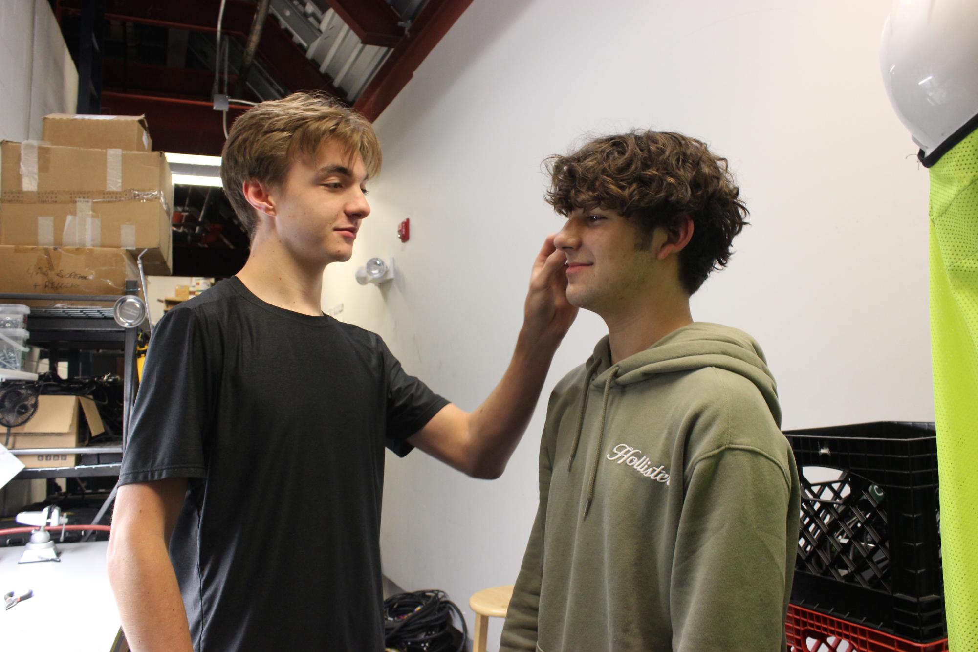 Senior Joshua Minor puts a microphone on junior Owen Gaffey. All leads use a microphone to project their voice throughout the entire auditorium.
